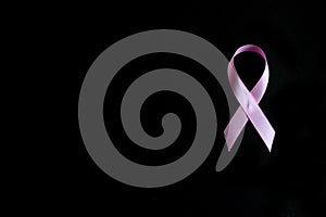 Pink ribbon, a symbol of breast cancer awareness, isolated on a black background. space for text