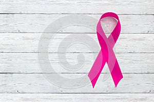 Pink ribbon on wooden background, the concept of female health, the fight against breast cancer