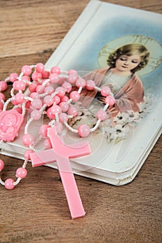 Pink rosary over a religious book