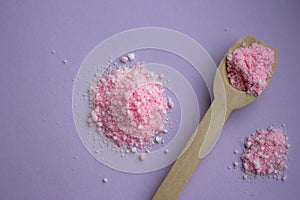Pink rose bath salt with wooden spoon on lilac background. Aroma spa concept. Aromatherapy.