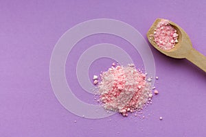 Pink rose bath salt with wooden spoon on lilac background with copy space. Aroma spa concept. Aromatherapy .