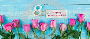 Pink rose flower and 8th March calendar on blue wood table background with copy space for text. Love, Equal and International