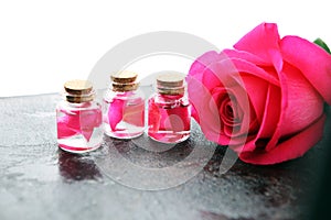 Pink rose flower and glass of bottle essential oil. spa and aromatherapy cosmetic concept