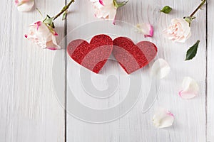 Pink rose flowers petals and handmade wooden glitter hearts on white rustic wood