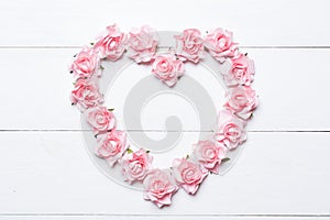 Pink rose heart over white wooden background