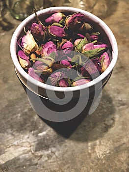 Pink Rose tea in package and white cup on the cement table with cafe light