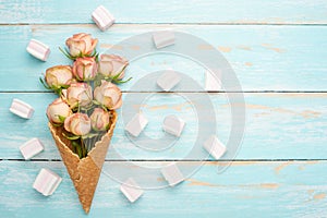 Pink roses in a cone with ice cream on a blue wooden background, concept gift for the beloved festive background, anniversary,