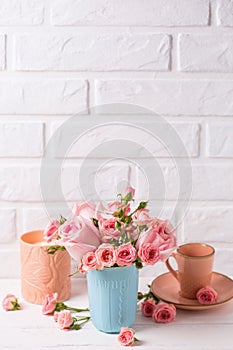 Pink roses flowers in blue cup, burning candle and little cup