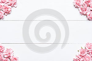 Pink roses frame on white wooden table with empty copyspace
