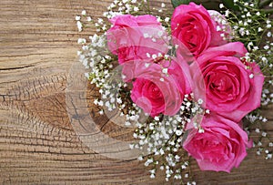 Pink Roses and Gypsophila on Wooden Background photo