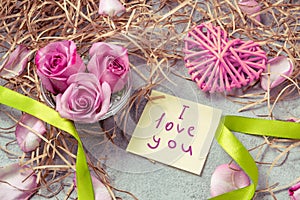 Pink roses, a heart and a note with the inscription I love you on the table-the concept of love and care