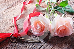 Pink roses and Love key shape on vintage wooden floor under soft warm light. Backdrop for Valentine's day