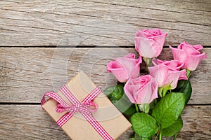 Pink roses and valentines day gift box over wooden table