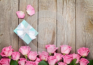 Pink roses and valentines day gift box over wooden table