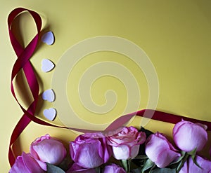 Pink roses, white hearts and ribbon on yellow background. Valentines day background.