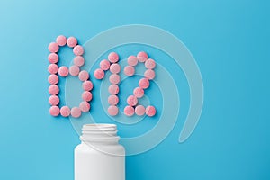 Pink round vitamins B12 shaped pills on a blue background spilled from a white can