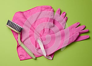 Pink rug, rubber gloves for cleaning, brushes on a green background, flat lay