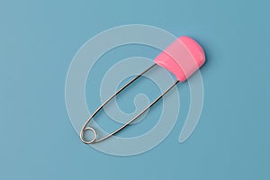 Pink safety pin isolated on a blue background