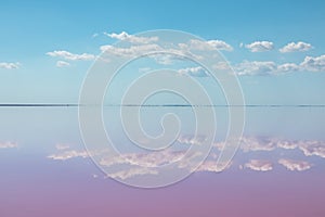 Pink salt lake water mirror with clouds, blue sky