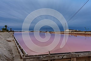 Pink salt pool at sunrise with dark clouds, ultra long exposure