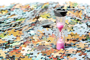 Pink sand hourglass on puzzle pieces background