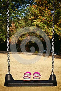 Pink sandals child on swing in the park