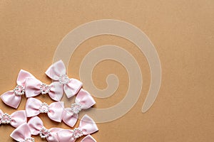 Pink satin bows with pearl hearts pattern on beige background. Festive concept for St Valentine`s Day