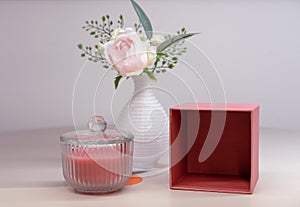 Pink scented candle in a glass candlestick and vase with a flower