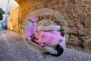 Pink scooter at a stone wall, Rhodes