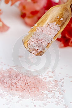 Pink sea salt dripping from a wooden spoon