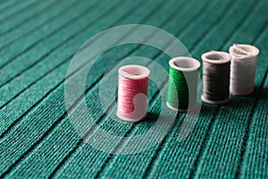 Pink sewing thread with other colorful threads on the green textile background - Image