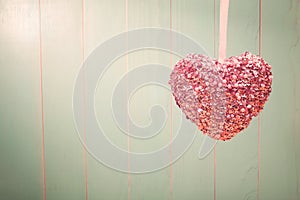 Pink shiny heart on vintage green wood background