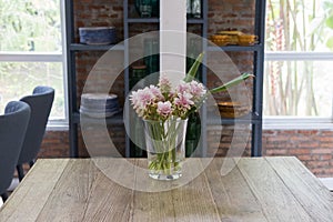 pink siam tulip flower in vase on wood table near window. decoration and interior