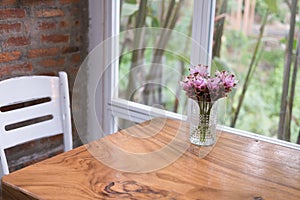 pink siam tulip flower in vase on wood table near window. decoration and interior