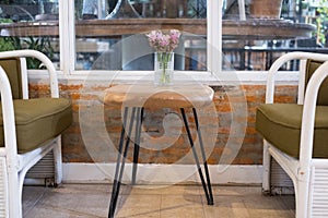 pink siam tulip flower in vase on wood table, white rattan wicker chair near window. decoration and interior