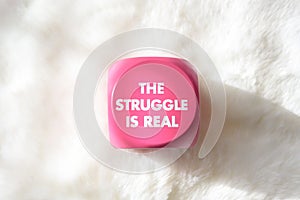 Pink sign with white lettering that says the struggle is real