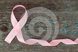 Pink silk - breast cancer awareness symbol on the wooden background with copy space