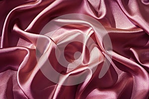 Pink silk satin. Shiny fabric surface. Wavy folds. Beautiful background.