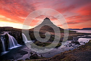 Pink skies over the famous kirkjufellsfoss waterfall in the icelandic landscape during sunset.