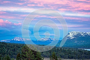 Pink skies and sunset colors over beautiful landscape scenery with snow capped mountains