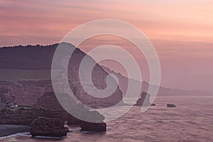 Pink sky, cliffs and sea just before sunrise