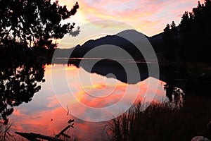 Pink sky over the lake in Rocky Mountain National Park during golden sunrise in Colorado