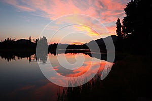 Pink sky over the lake in Rocky Mountain National Park during golden sunrise in Colorado