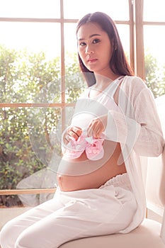 Pink small shoes on belly of pregnant woman
