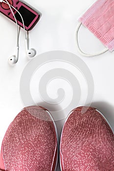 Pink sneakers, headphone and pink mask against white background. Sport in pandemia concept photo