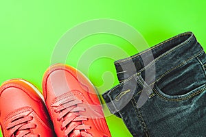Pink sneakers and jeans on green background. Concept of sport and healthy lifestyle.