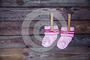 Pink socks hang on the clothespin wooden background