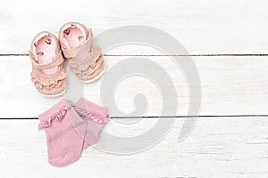 Pink socks and shoes for little girl on a white wooden background. Copy space