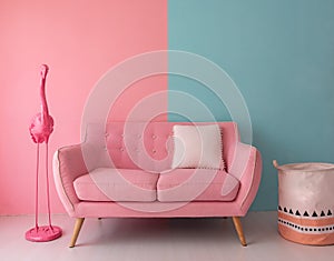 The pink sofa which has a white pillow is set in living room which has blue and pink wall