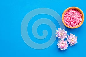 Pink spa salt for aroma therapy with flower fragrance on blue background top view copyspace